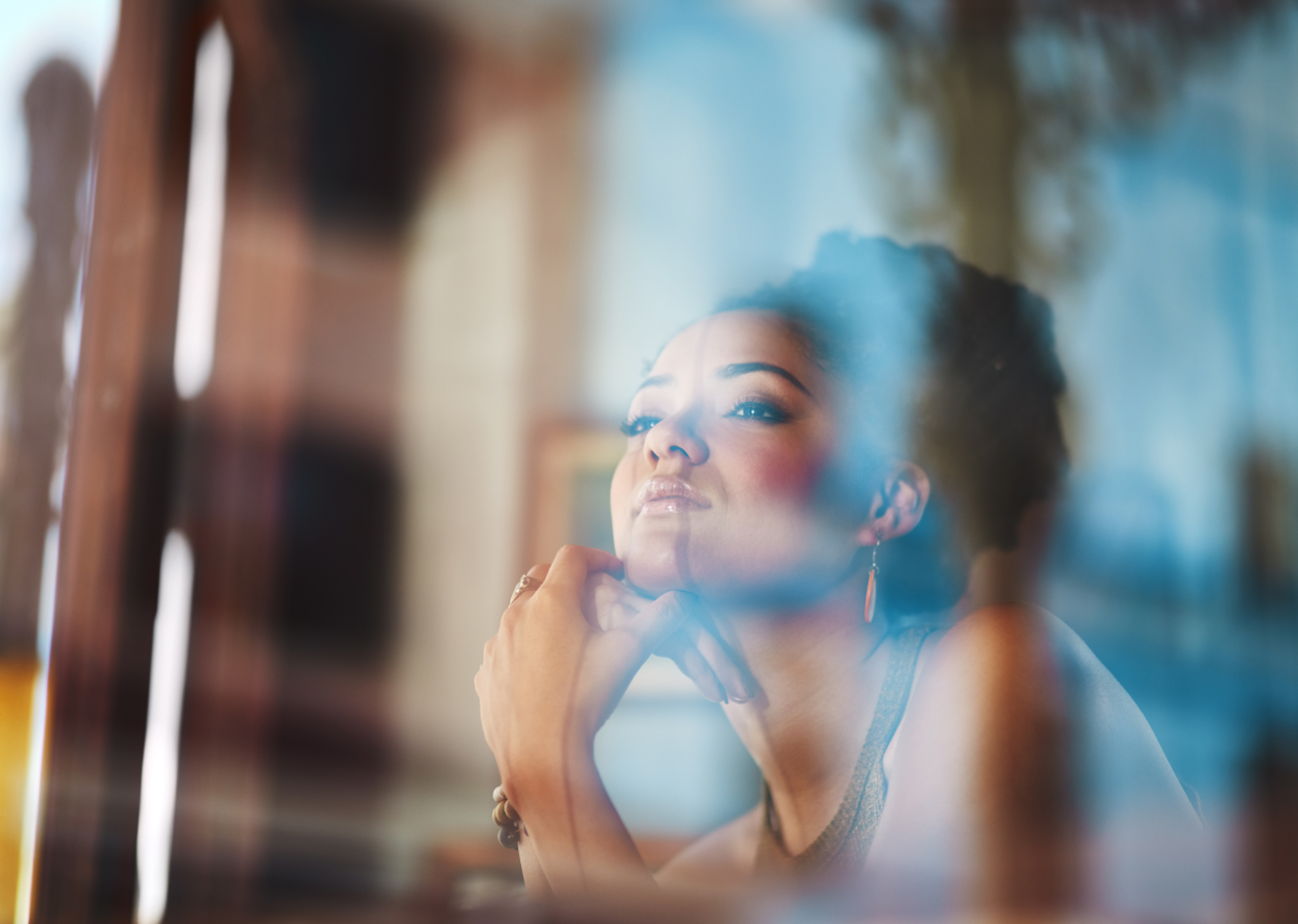 Person by window Adult woman looking out a window in a reflective moment, representing thoughtful therapy support